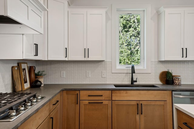 kitchen featuring white cabinetry, appliances with stainless steel finishes, decorative backsplash, and a sink