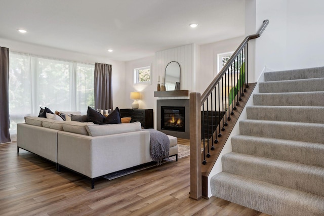 living area featuring stairs, wood finished floors, a large fireplace, and recessed lighting