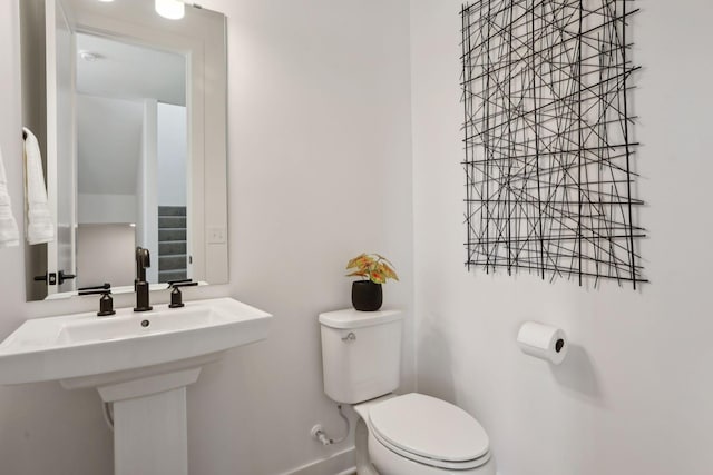 half bath featuring baseboards, a sink, and toilet