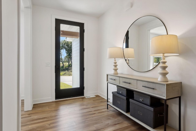 foyer with light wood-style floors and baseboards