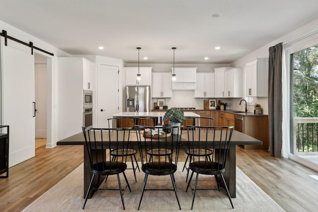 dining area with recessed lighting, light wood-style floors, and a barn door