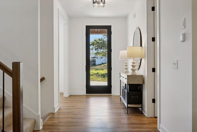 doorway to outside featuring wood finished floors, stairs, and baseboards