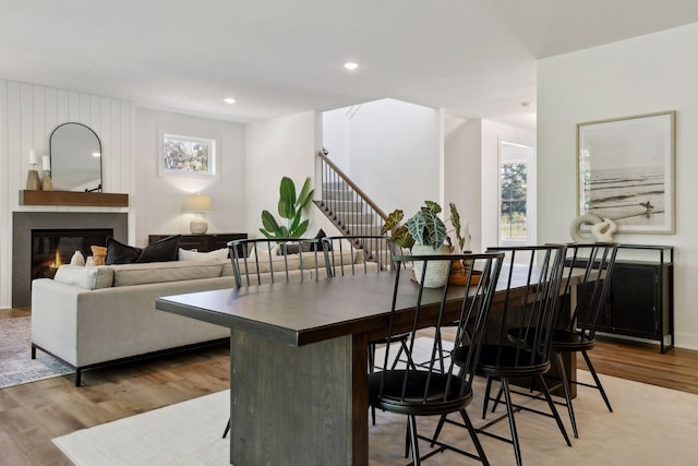 dining area with recessed lighting, wood finished floors, a large fireplace, and stairs