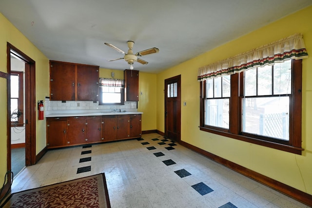 kitchen with a ceiling fan, light floors, baseboards, light countertops, and backsplash