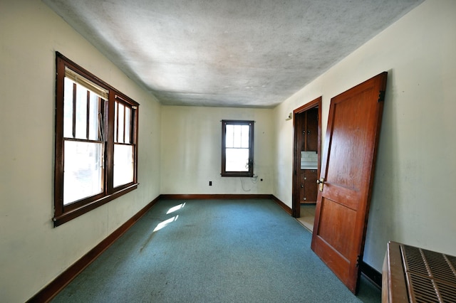 carpeted spare room featuring baseboards and a textured ceiling