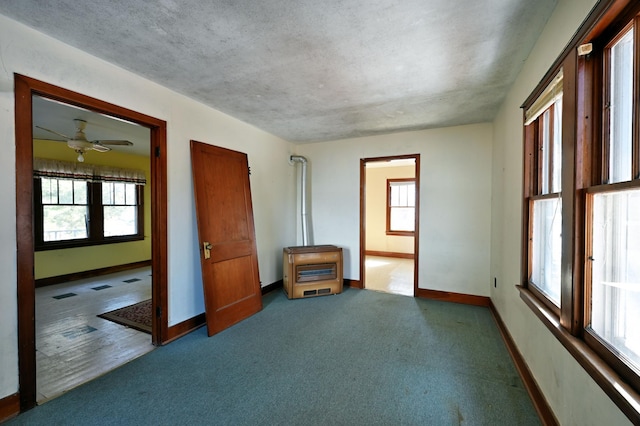 carpeted spare room featuring a ceiling fan, baseboards, and a textured ceiling