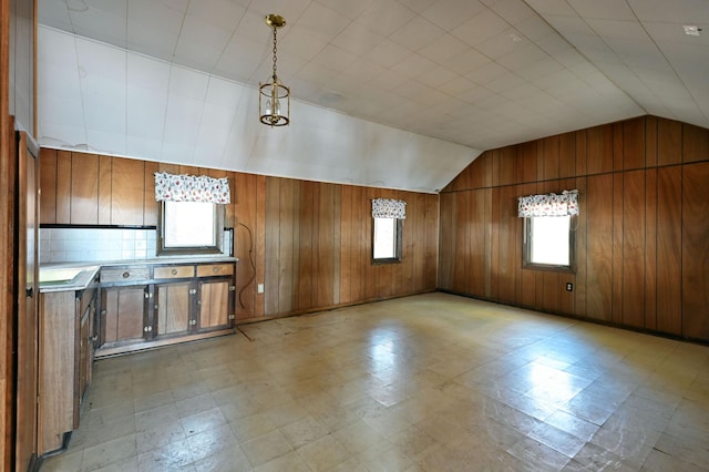 bonus room with vaulted ceiling, wooden walls, and light floors