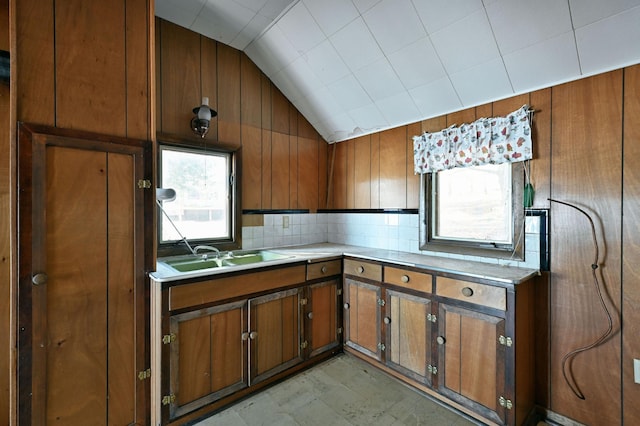 kitchen with brown cabinetry, light countertops, lofted ceiling, and a sink