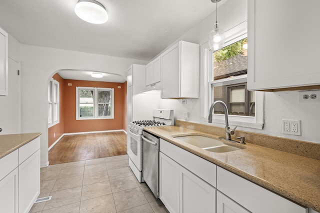 5413 42nd Ave S, Minneapolis, MN 55417 - kitchen featuring a sink, white gas stove, white cabinets, and arched walkways