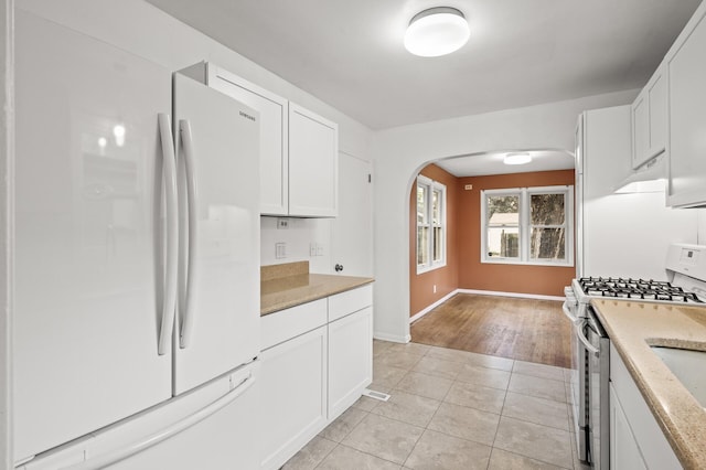 5413 42nd Ave S, Minneapolis, MN 55417 - kitchen featuring freestanding refrigerator, range with gas stovetop, arched walkways, and white cabinetry