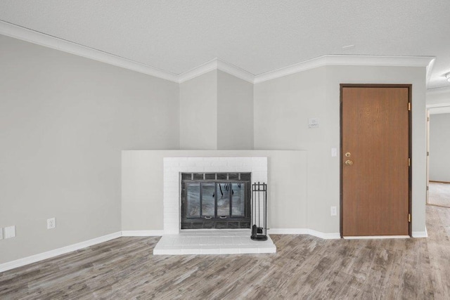 unfurnished living room featuring a fireplace, wood finished floors, baseboards, and ornamental molding