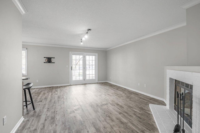 unfurnished living room featuring a textured ceiling, wood finished floors, and ornamental molding