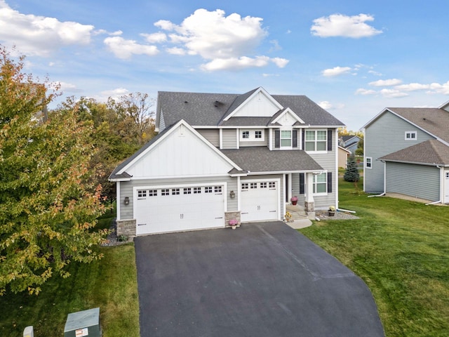 view of front of property featuring a front yard, driveway, a shingled roof, stone siding, and board and batten siding