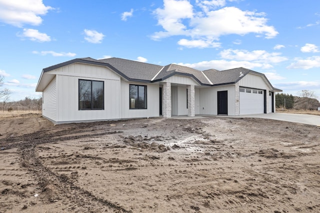 view of front of property with board and batten siding, a garage, driveway, and a shingled roof