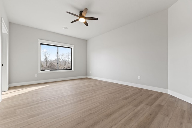 spare room featuring baseboards, ceiling fan, and light wood finished floors