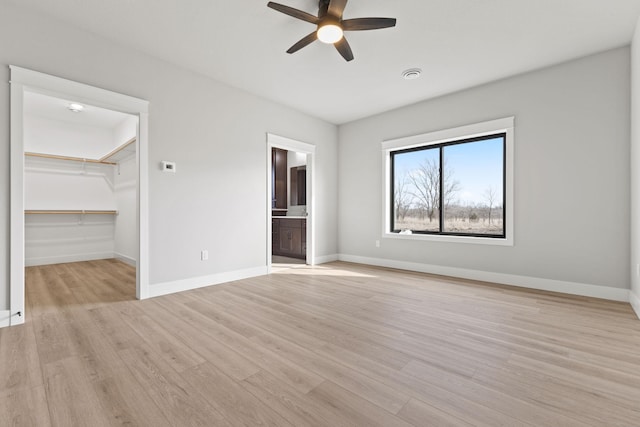 unfurnished bedroom with light wood-type flooring, baseboards, and a spacious closet