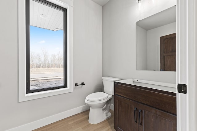 bathroom featuring baseboards, toilet, wood finished floors, and vanity