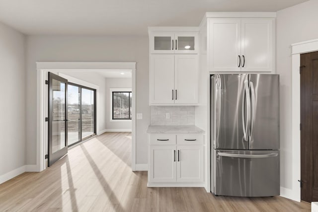 kitchen featuring tasteful backsplash, light wood-type flooring, white cabinetry, and freestanding refrigerator