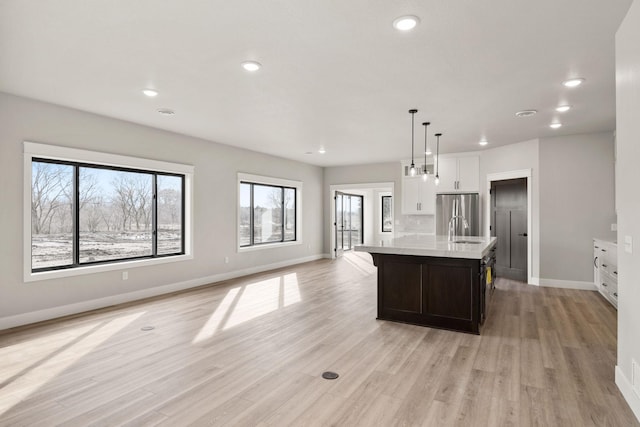 kitchen with open floor plan, recessed lighting, light wood-style flooring, freestanding refrigerator, and a sink