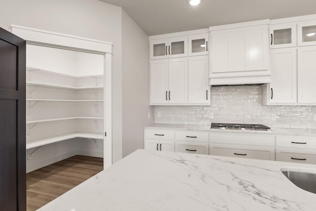 kitchen featuring light stone counters, decorative backsplash, stainless steel gas stovetop, and white cabinetry