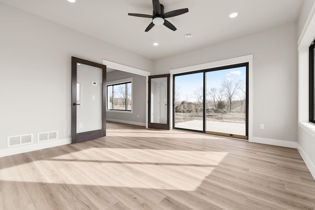 empty room featuring light wood finished floors, visible vents, and baseboards