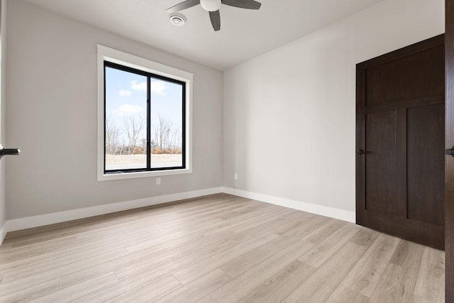 spare room with visible vents, a ceiling fan, light wood-type flooring, and baseboards