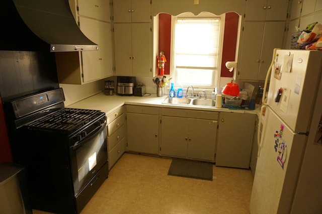 kitchen featuring light countertops, freestanding refrigerator, gas stove, wall chimney exhaust hood, and a sink