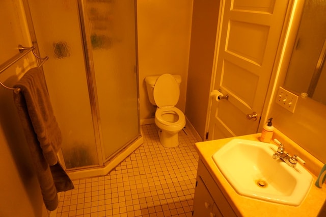 bathroom with vanity, baseboards, tile patterned flooring, a shower stall, and toilet