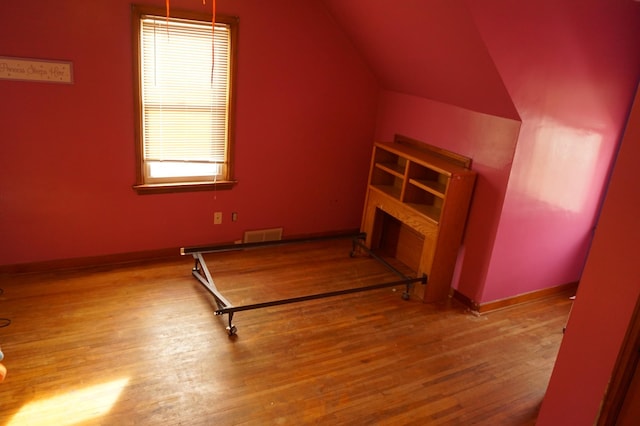 bonus room featuring vaulted ceiling, visible vents, baseboards, and wood finished floors