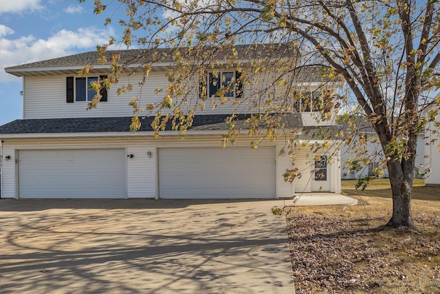 view of front of property with an attached garage, concrete driveway, and roof with shingles