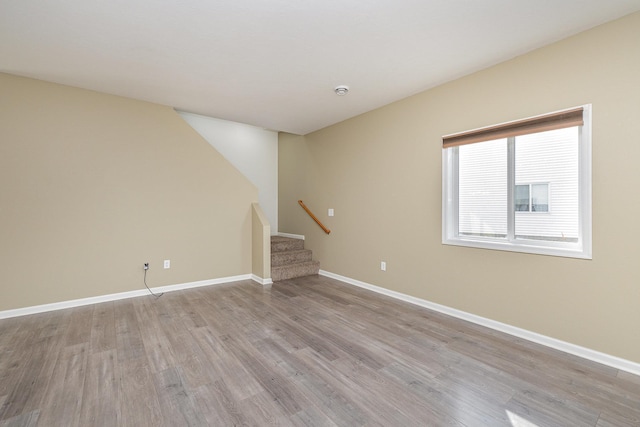 unfurnished room featuring stairway, baseboards, and wood finished floors