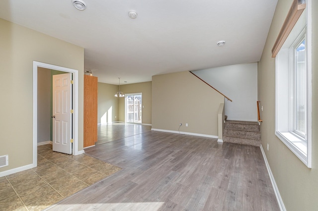 unfurnished living room with stairway, baseboards, visible vents, and wood finished floors