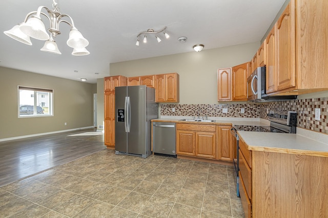 kitchen with baseboards, a sink, stainless steel appliances, light countertops, and tasteful backsplash