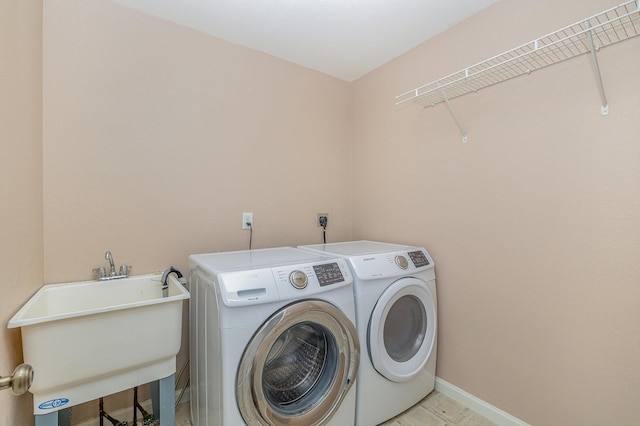 clothes washing area with a sink, baseboards, laundry area, and washing machine and clothes dryer