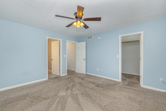 unfurnished bedroom featuring visible vents, a walk in closet, carpet, baseboards, and a ceiling fan