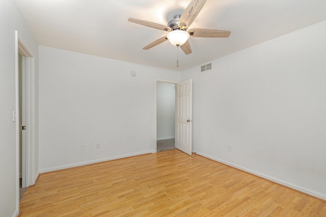 spare room featuring ceiling fan, light wood-style floors, visible vents, and baseboards