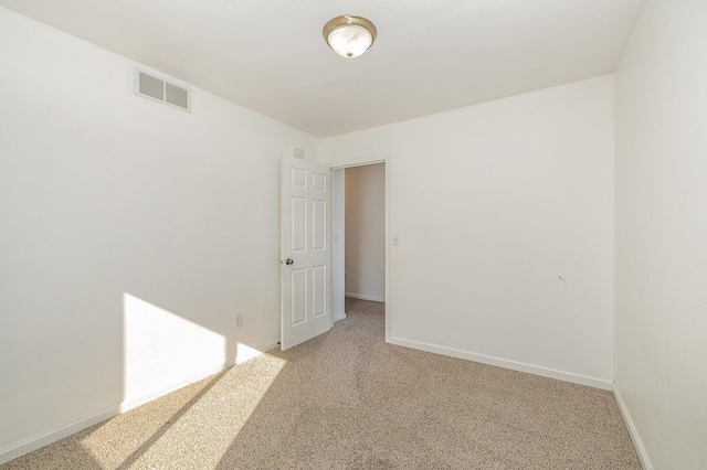 empty room with visible vents, light colored carpet, and baseboards