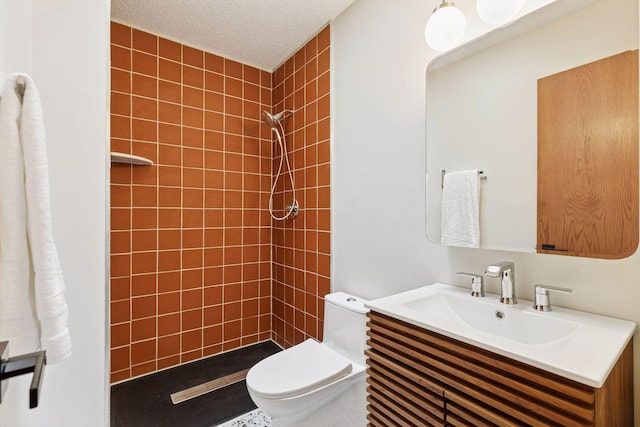 full bath featuring a tile shower, a textured ceiling, toilet, and vanity