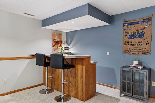 bar featuring baseboards, visible vents, a bar, and carpet