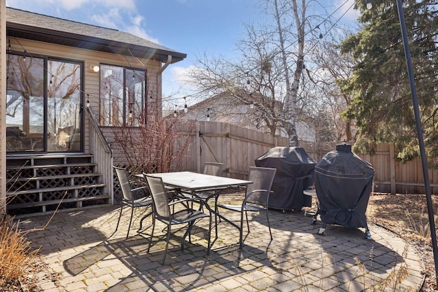 view of patio / terrace featuring grilling area, entry steps, outdoor dining area, and a fenced backyard