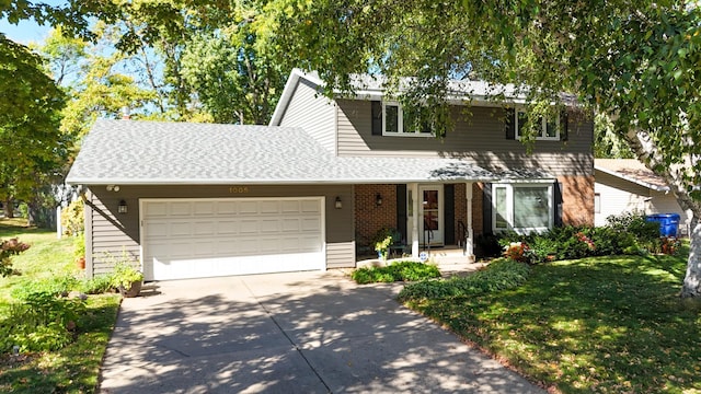 traditional-style house featuring brick siding, a shingled roof, a front lawn, a garage, and driveway