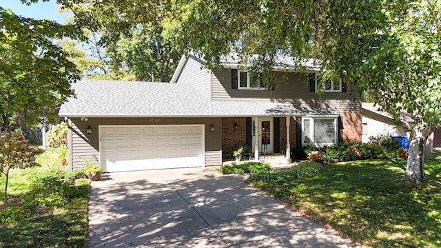 traditional home with a front yard, an attached garage, a shingled roof, concrete driveway, and brick siding