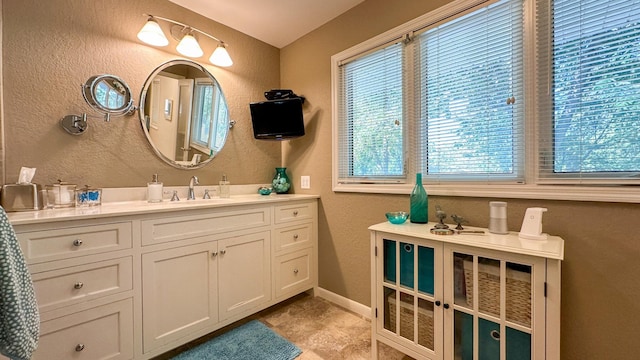 bathroom with vanity, a textured wall, and baseboards