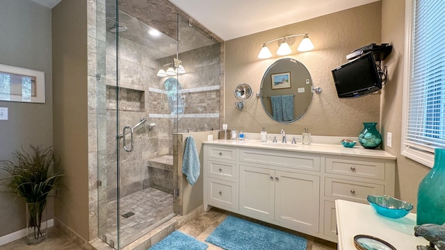 bathroom featuring baseboards, vanity, a shower stall, and a textured wall