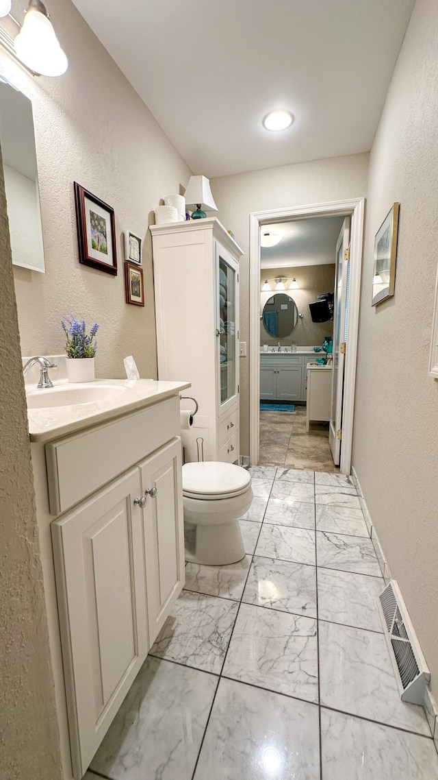 bathroom with vanity, baseboards, visible vents, toilet, and marble finish floor