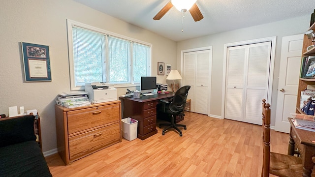 office space with light wood finished floors, baseboards, a textured ceiling, and a ceiling fan