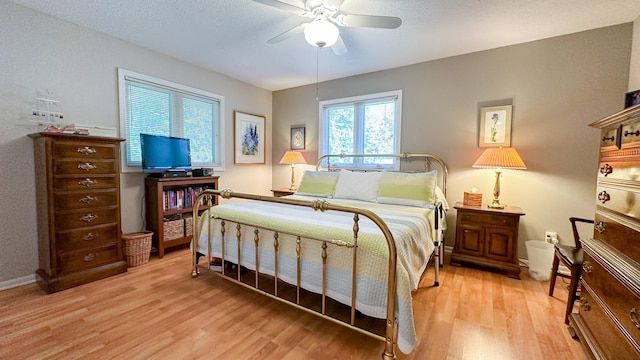 bedroom featuring a ceiling fan, baseboards, and light wood finished floors