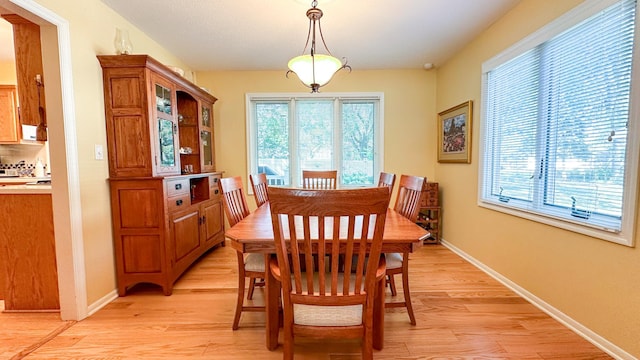 dining room with a wealth of natural light, baseboards, and light wood finished floors