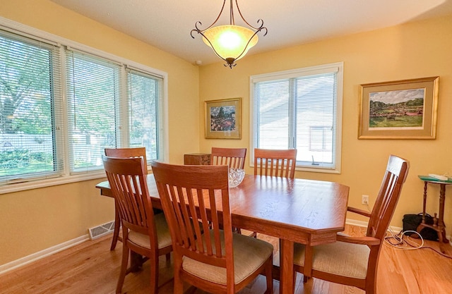 dining area with visible vents, light wood-style flooring, and baseboards