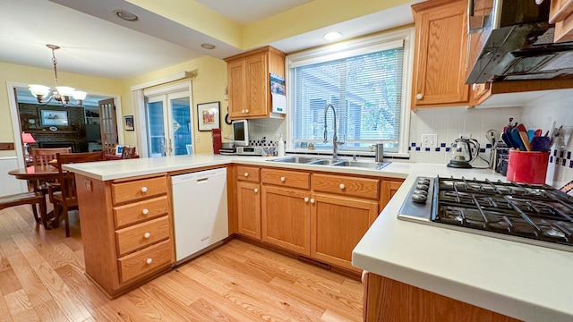 kitchen featuring light wood finished floors, a sink, a peninsula, and white dishwasher